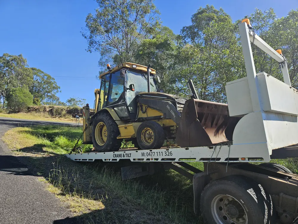 Backhoe loader secured on the tilt tray truck