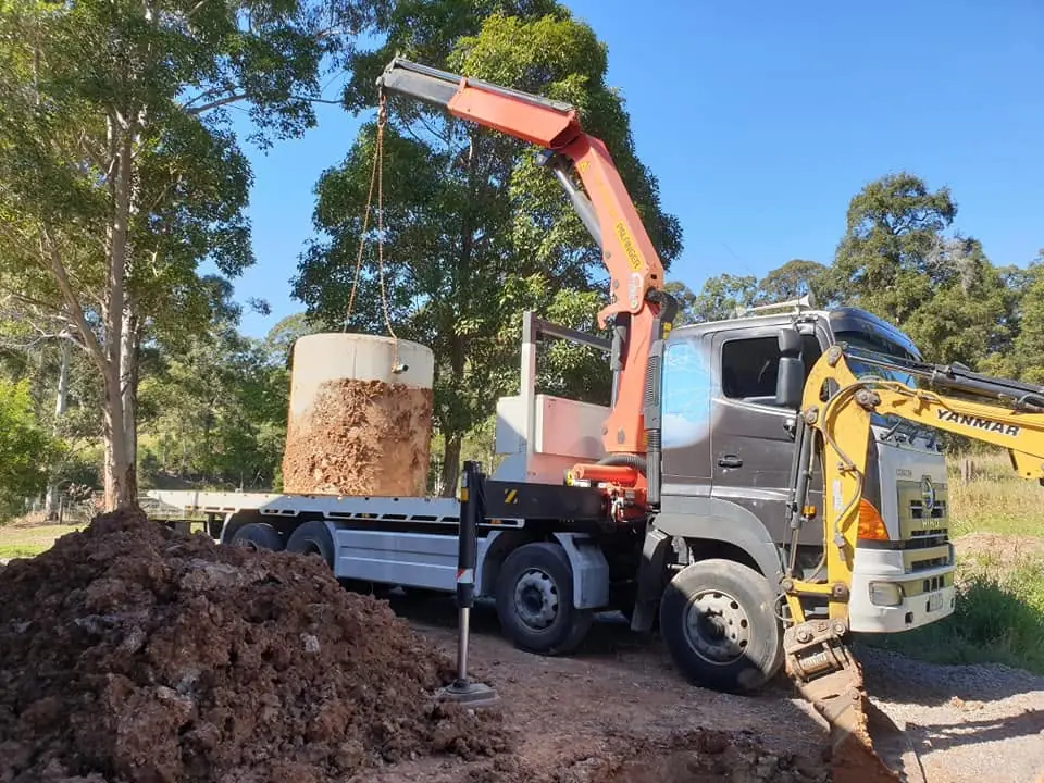 Crane truck lifting a large tree stump on a work site