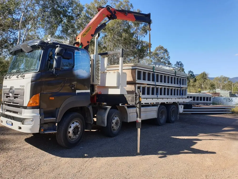 Crane truck parked with outriggers deployed and crane folded above the tray