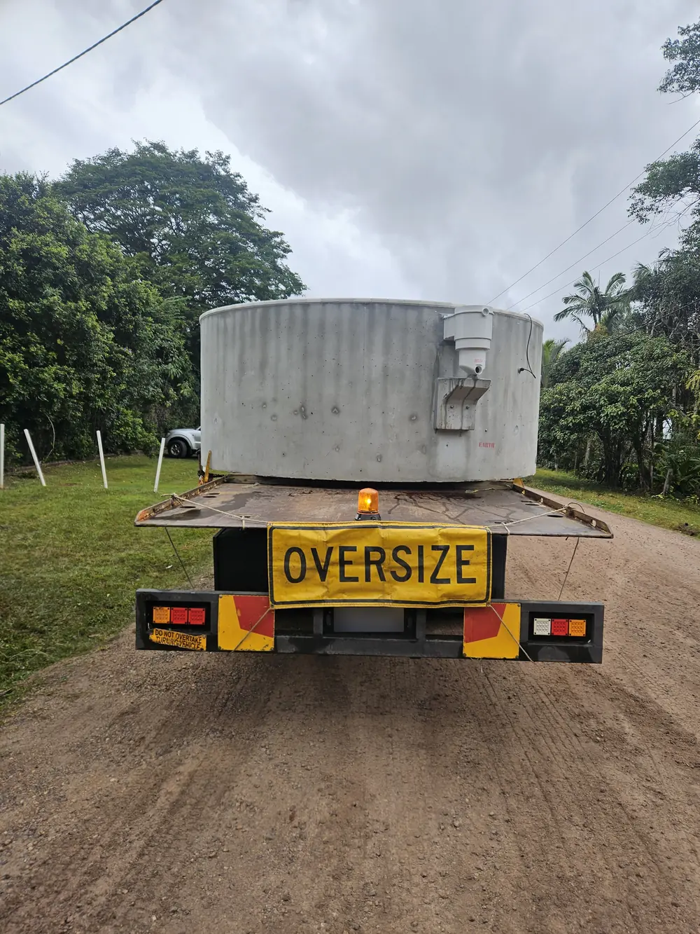 Large cylindrical tank secured on a tilt tray truck, viewed from behind