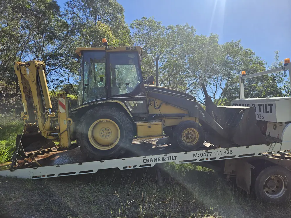 Backhoe loader secured on tilt tray